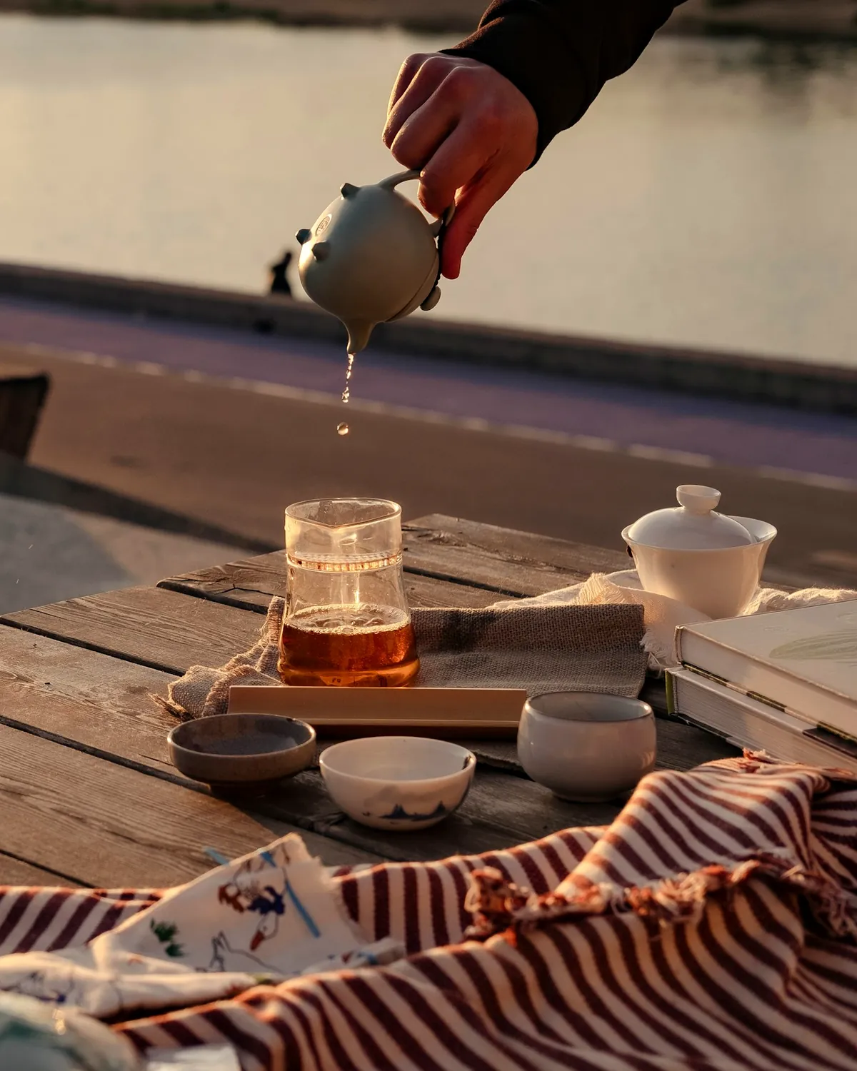 Juego de té chino sobre una mesa de madera al aire libre, con luz cálida de primera hora
